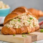 head on close up view of a ham salad sandwich recipe on a croissant on a cutting board with fresh parsley on it and around it - 13