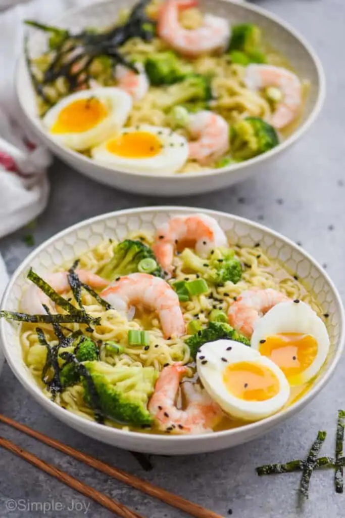 side view of a two bowls of simple homemade ramen with shrimp, broccoli, seaweed, and a soft boiled egg
