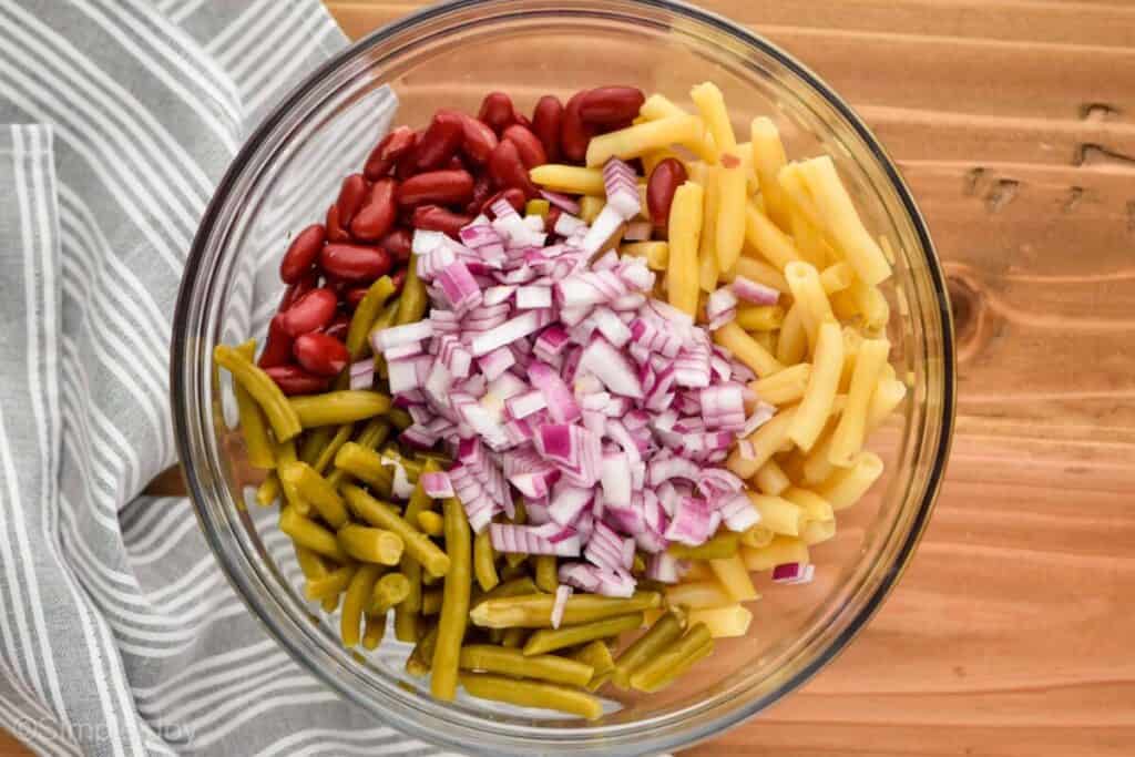 ingredients for three bean salad in a glass bowl separated by ingredient