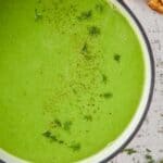 overhead view of a dutch oven with orange handles filled with pea soup garnished with fresh dill - 6