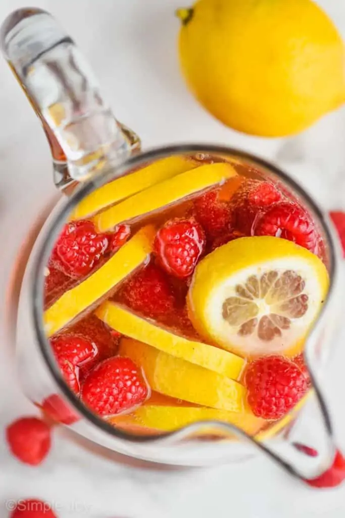 overhead view of a pitcher of rose sangria with fresh lemons and raspberries