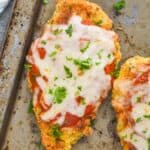overhead view of a piece of oven baked chicken parmesan on an old tray garnished with fresh parsley - 25