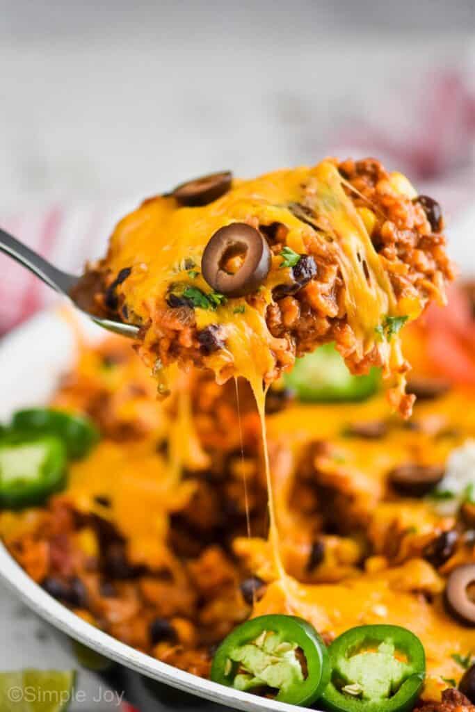 spoon dishing out cheesy taco casserole recipe from a skillet