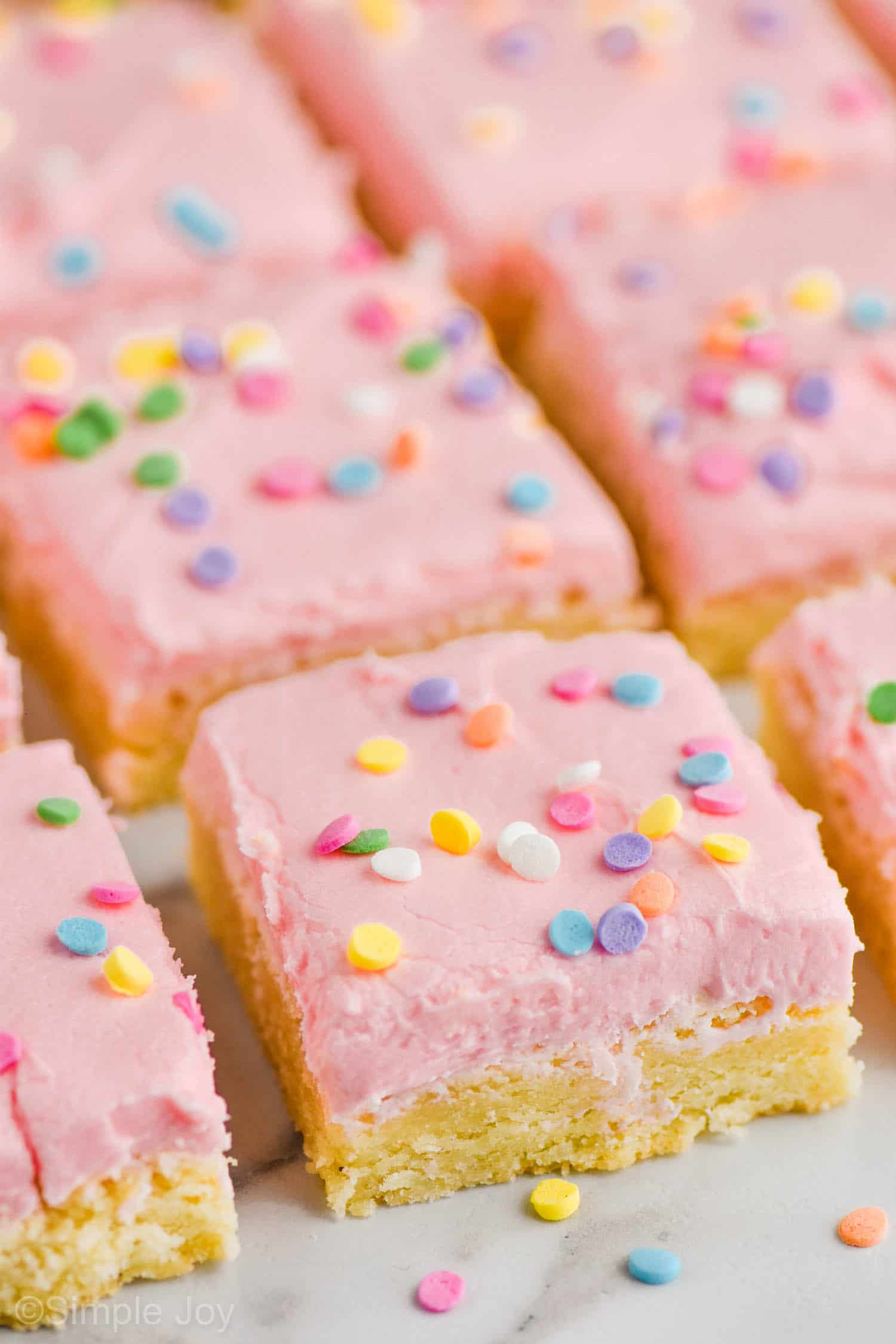 pulled back look at rows of sugar cookie bars with circle pastel sprinkles on a white surface