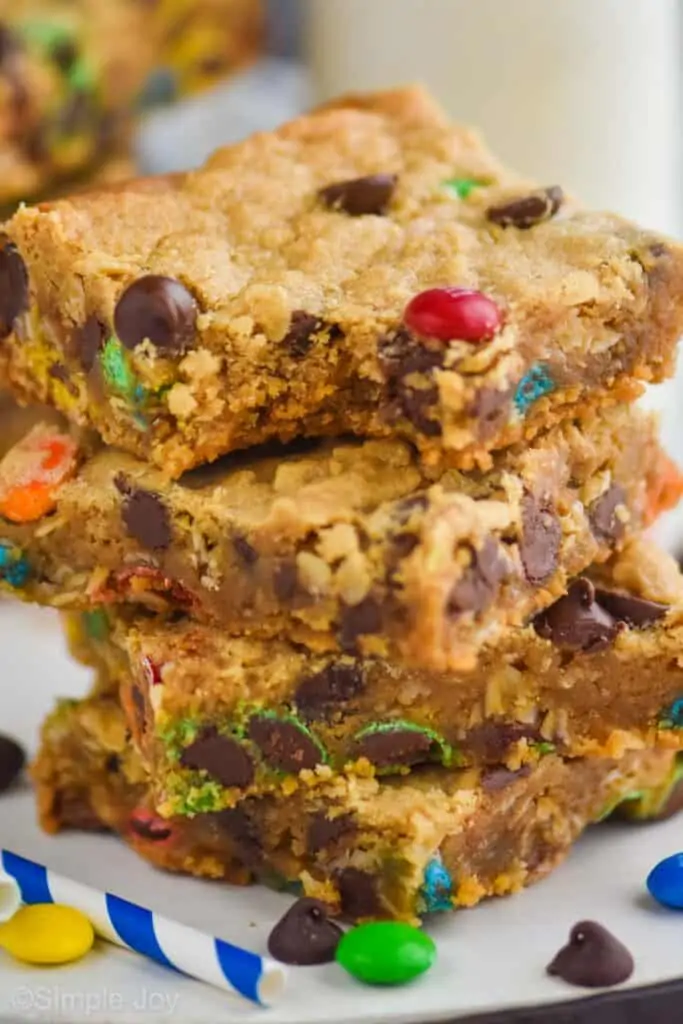 close up of four monster cookie bars with the a bite missing out of the top one