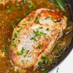 a pan fried pork chop in a a frying pan, with easy onion sauce around it and chopped parsley on top - 6