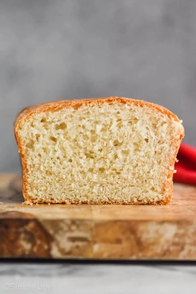 a straight on look at white bread sitting on a cutting board against a gray background