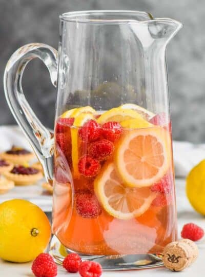 tall pitcher filled with sparkling rose sangria, fresh raspberries, and lemon slices