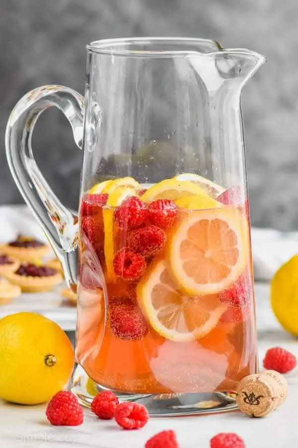 tall pitcher filled with sparkling rose sangria, fresh raspberries, and lemon slices