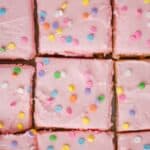 overhead view of sugar cookie bars that are cut and close together, frosting with pink frosting and pastel circle sprinkles