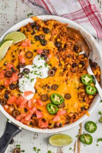 overhead view of an easy taco casserole recipe in a skillet, being spooned out, you can see beans, meat, rice, and corn