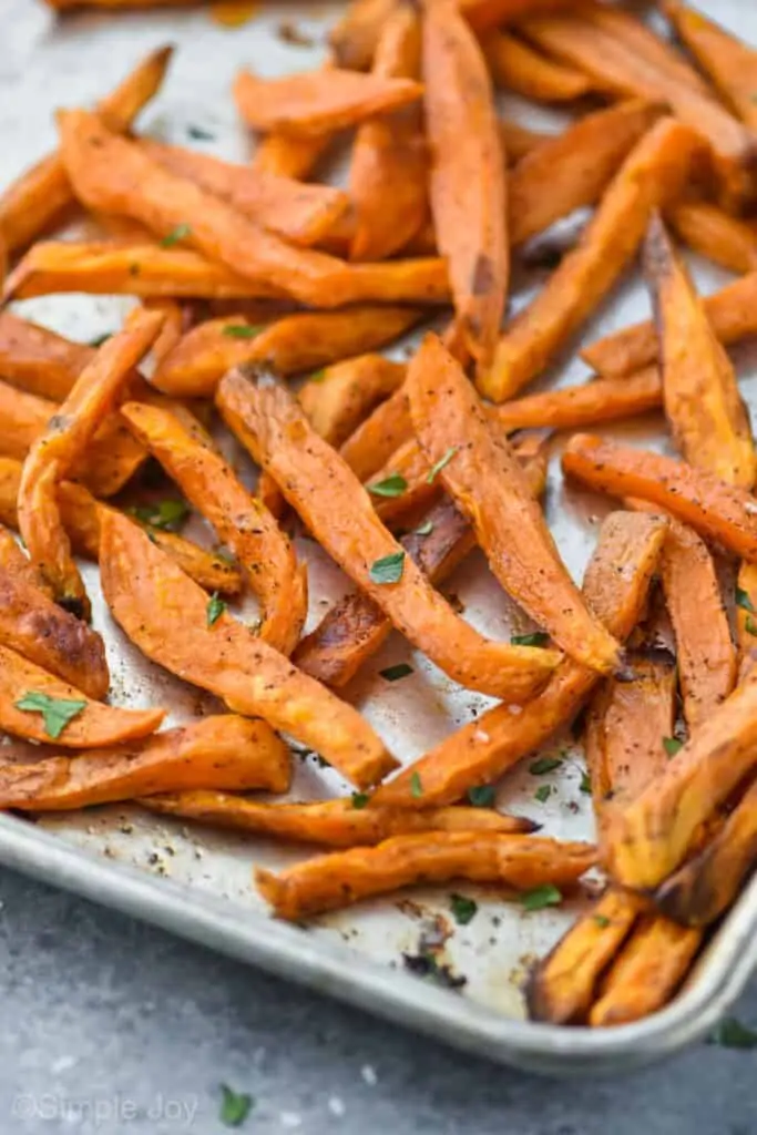 sweet potato fries on a baking sheet garnished with fresh parsley