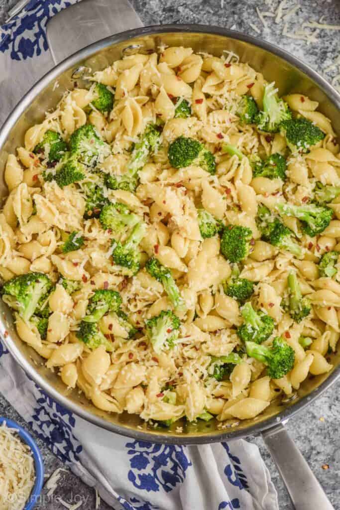 close up overhead view of broccoli pasta recipe made with shells, broccoli florets, red pepper flakes and freshly grated parmesan cheese