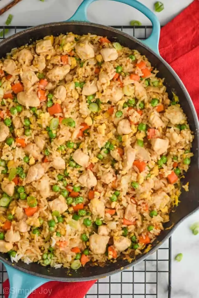 overhead close up view of teal skillet filled with chicken fried rice on a wire cooling rack with a red napkin