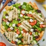 overhead view of a greek salad with chicken slices in a big serving bowl, garnished with fresh parsley, and pita chips off to the side - 7