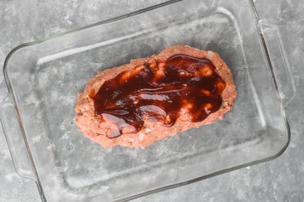 overhead view of a raw meatloaf topped with BBQ sauce that has been free formed in a baking dish