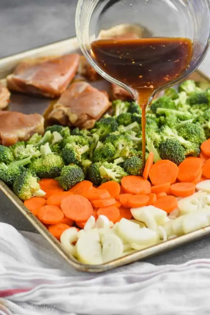 teriyaki marinade being poured over vegetables and chicken thighs