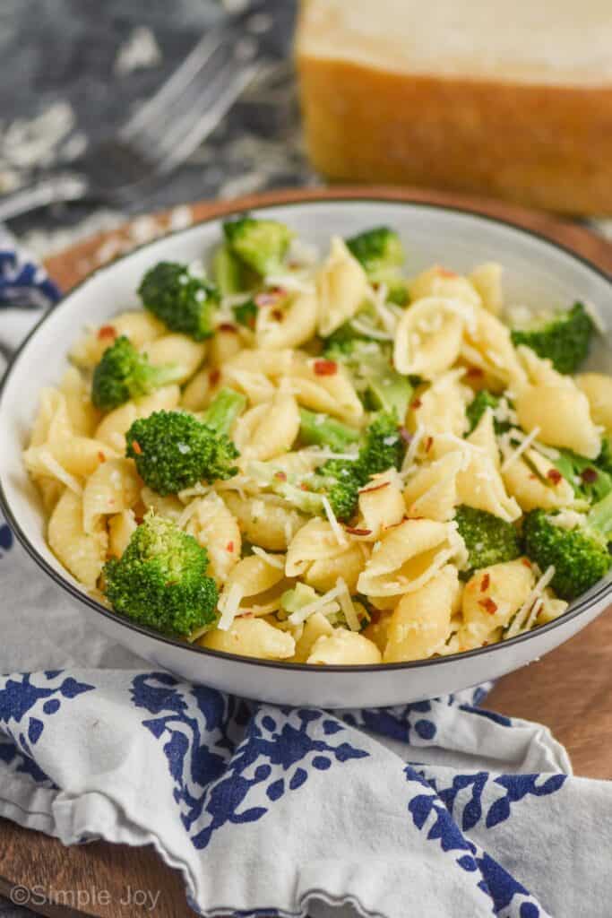 front view of a bowl of pasta shells with broccoli garnished with red pepper flakes and freshly grated parmesan cheese
