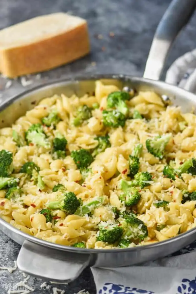 front view of a metal skillet holding easy broccoli pasta recipe with shells, broccoli, parmesan cheese, and red pepper flakes