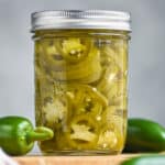 small mason jar filled with pickled jalapeños, yellow green in color and packed in liquid