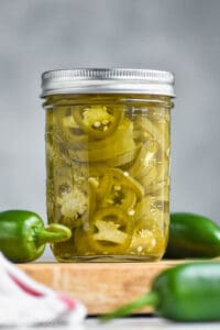 small mason jar filled with pickled jalapeños, yellow green in color and packed in liquid