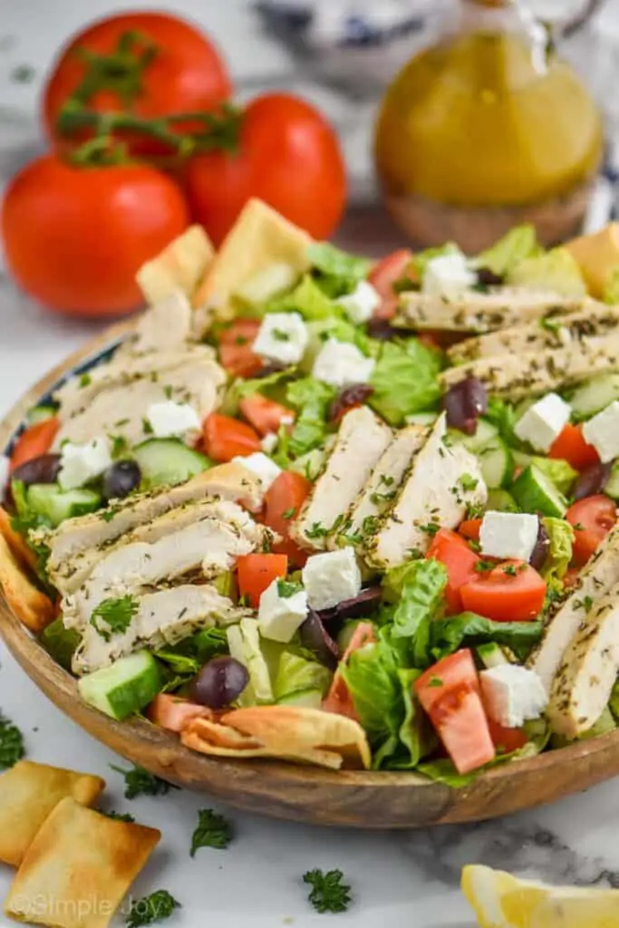 side view of a greek salad with chicken and served with pita chips