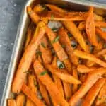 overhead photo of baked sweet potato fries on a baking sheet garnished with fresh parsley