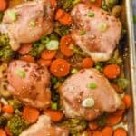 teriyaki chicken thighs on a baking sheet with broccoli, onions, and carrots, garnished with sesame seeds and green onions - 7