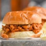 a turkey sloppy Joe on a white bun sitting on an overturned rimmed metal baking sheet with ruffled potato chips around it - 6