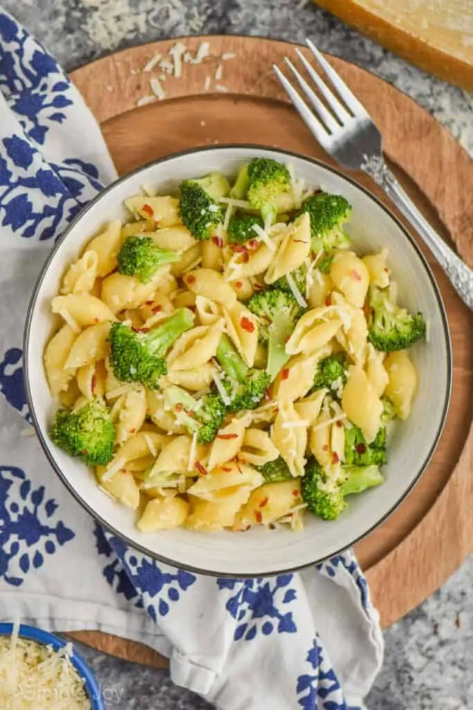 overhead view of pasta shells and broccoli in a bowl with parmesan cheese and red pepper flakes