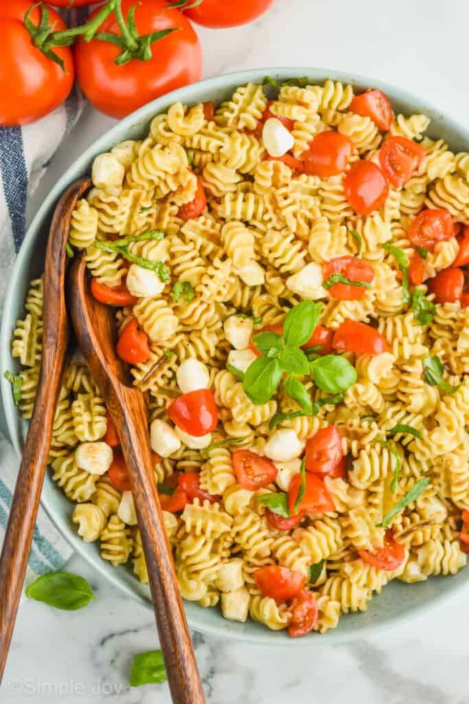 overhead view of large bowl full of caprese pasta salad, garnished with fresh basil leaves