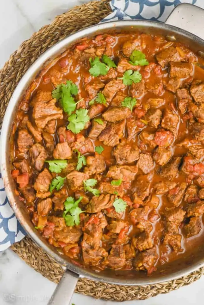 overhead view of beef curry in a skillet garnished with cilantro