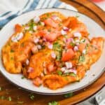 three chicken enchiladas on a plate garnished with cut up cilantro, red onions, and tomatoes - 5