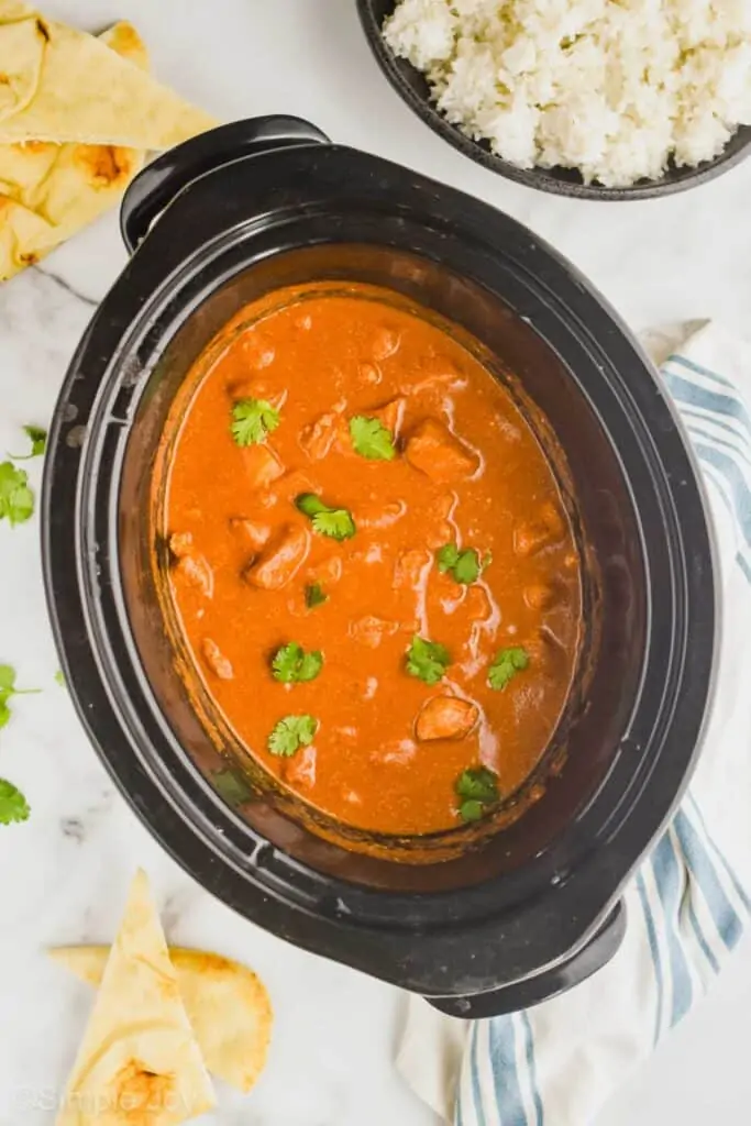 overhead picture of a crockpot filled with butter chicken recipe garnished with fresh cilantro