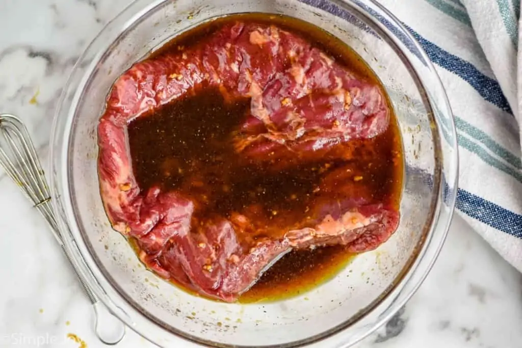 overhead of a flank steak in a bowl with marinade