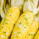 up close of fresh corn that has been grilled with butter and fresh parsley