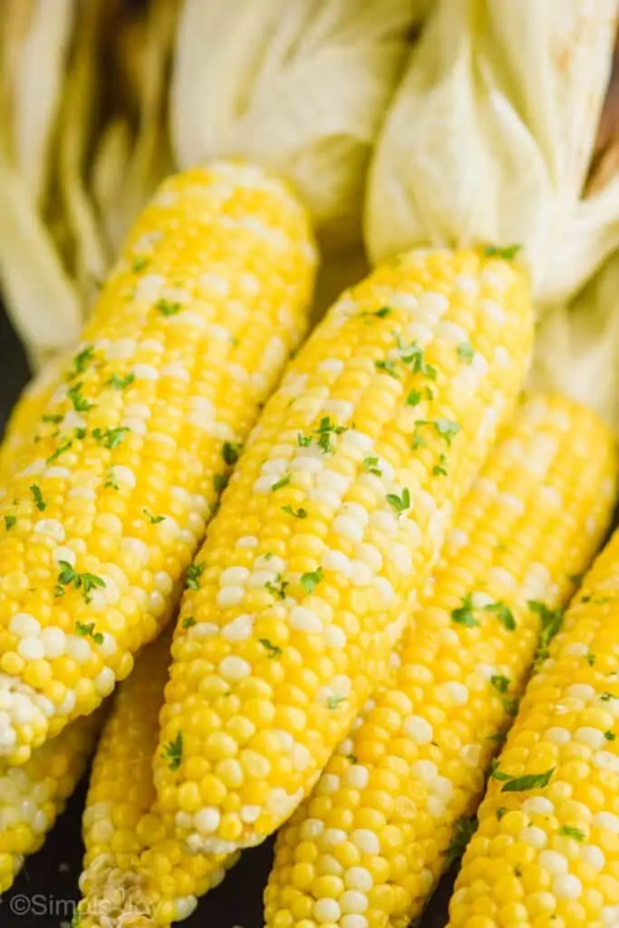 up close of fresh corn that has been grilled with  butter and fresh parsley