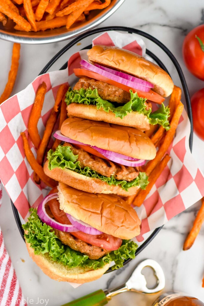 Overhead photo of a basket of Turkey Burgers served on buns and garnished with lettuce, tomato, and onion. French fries beside basket of Turkey Burgers.