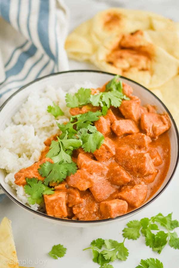 crockpot butter chicken recipe in a bowl with rice and garnished with fresh cilantro