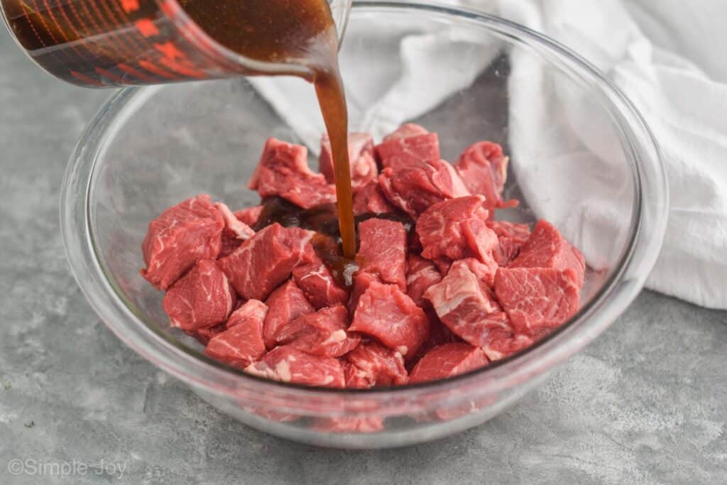 steak kabob marinade being poured over cubed top sirloin