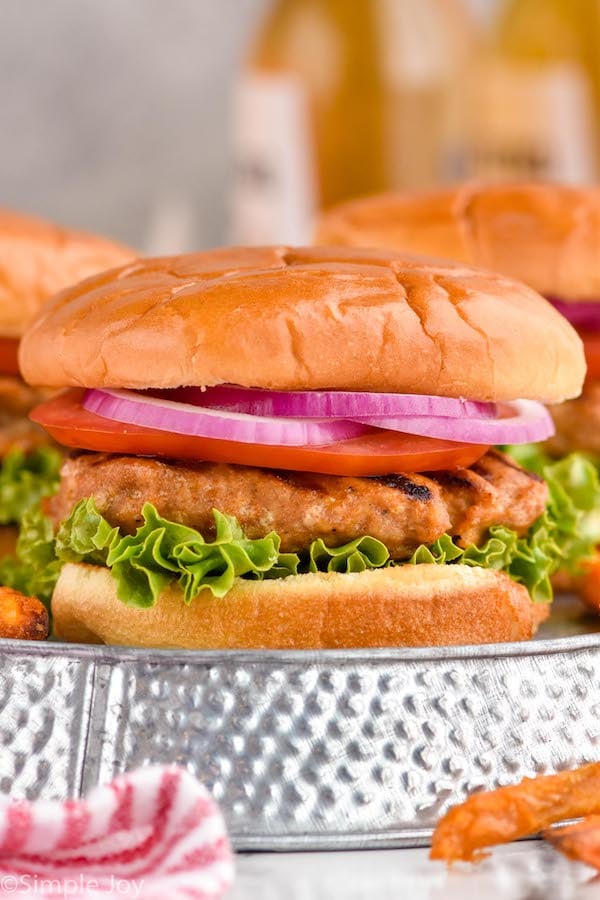 Close up photo of Turkey Burger recipe served in a bun garnished with lettuce, tomato, and onion.