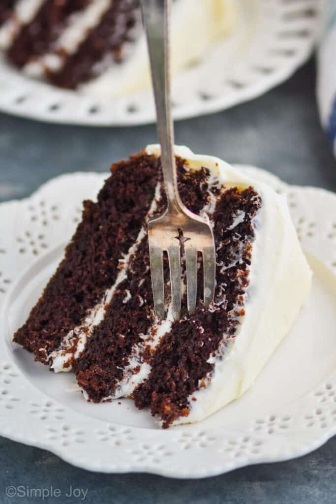piece of zucchini cake with cream cheese frosting on a plate with a fork sticking out