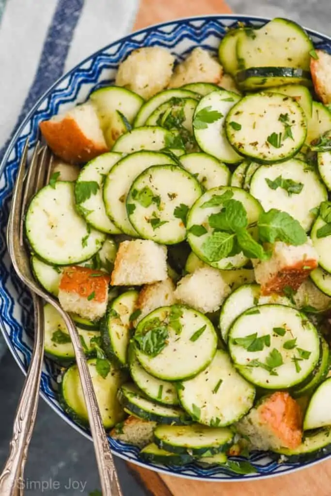 overhead view of a zucchini salad with big bread cubes and fresh mint in a bowl