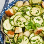 overhead view of a zucchini salad with big bread cubes and fresh mint in a bowl