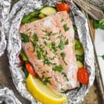 baked salmon in a foil packet garnished with flat leaf parsley and a fresh lemon wedge - 8