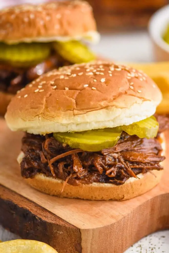 close up of bbq beef on a sesame seed bun with two pickles on it