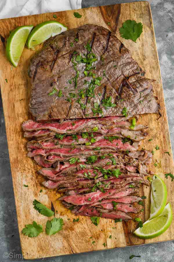 overhead view of a carne asada after being grilled - half the meat has been sliced thin and grill marks can be seen on the other half