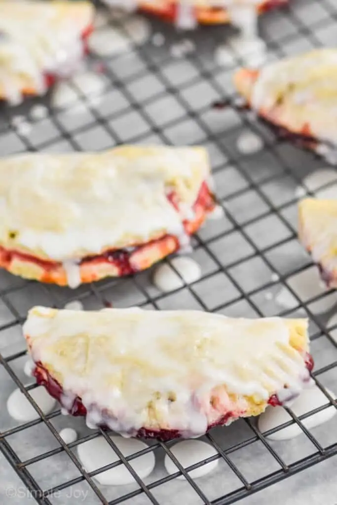 cherry hand pies on a cooling rack with glaze dripped over them