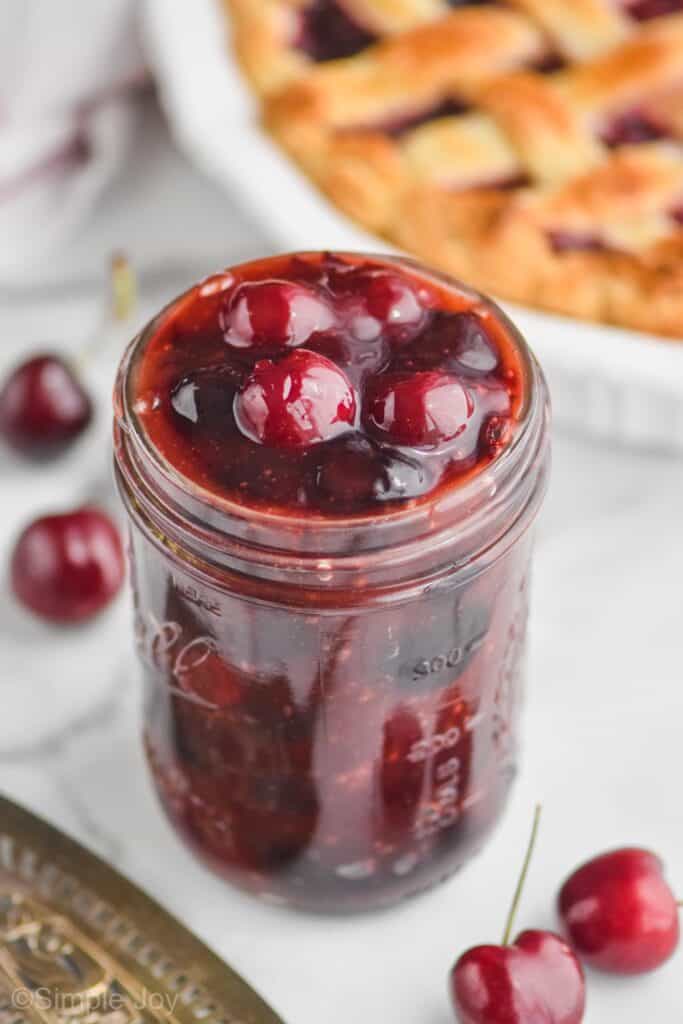 mason jar with cherry pie filling with cherry pie in the background