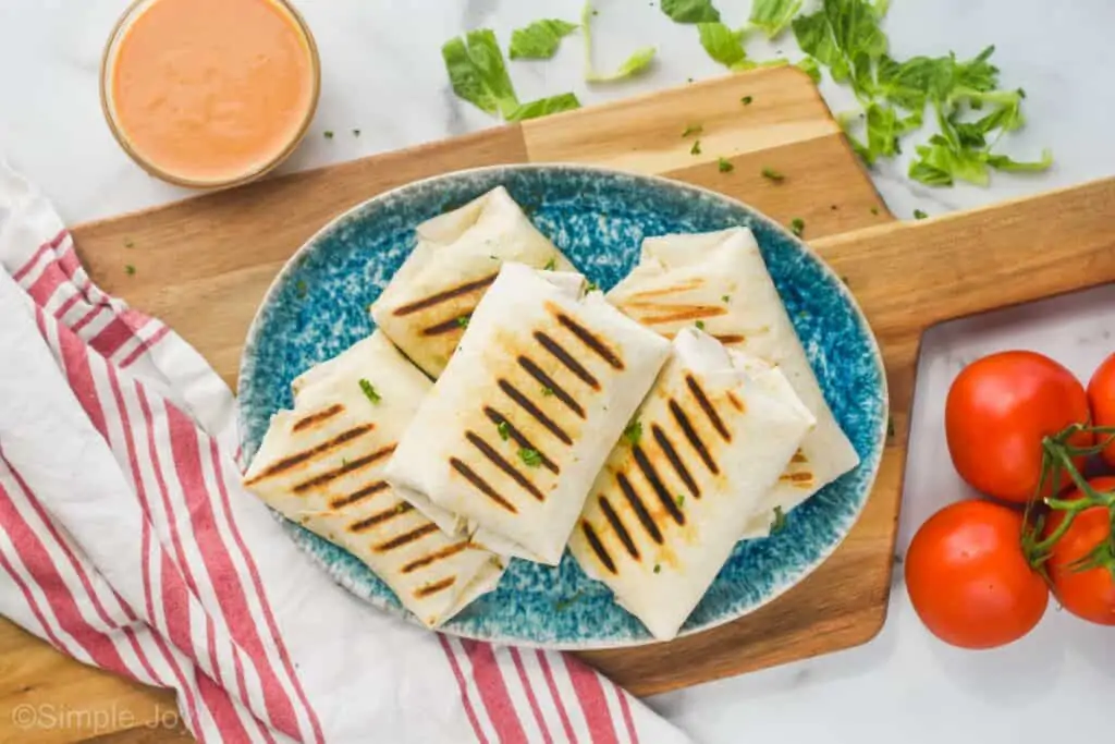 overhead of a platter holding five grilled chicken wraps